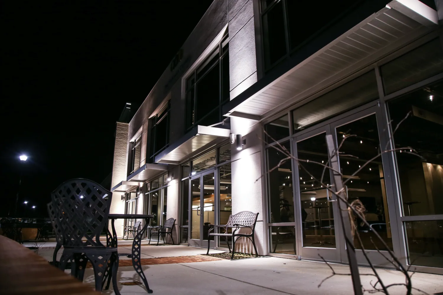 Exterior entrance of the McKissick Center at night, glowing under warm lights with patio seating.